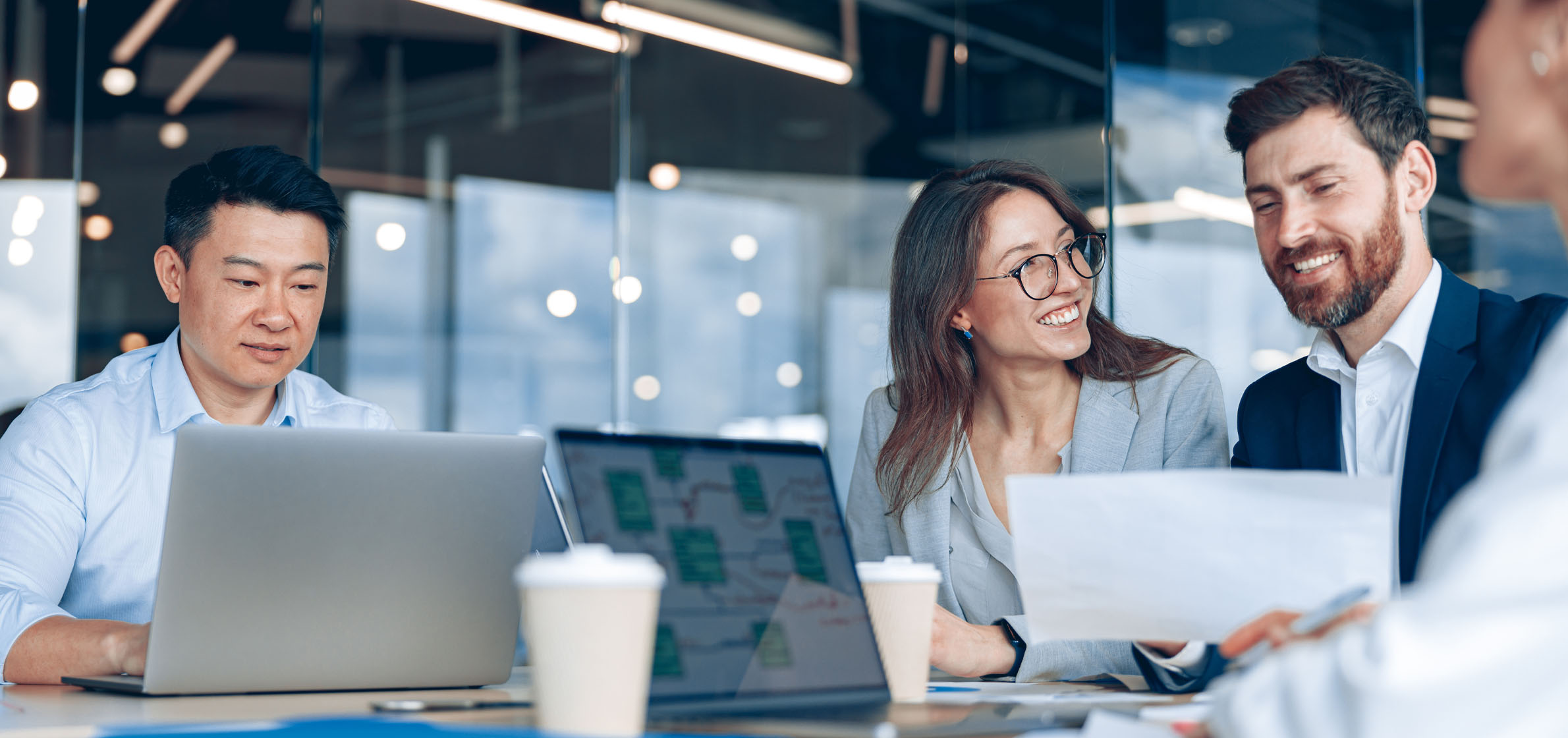 Employees collaborating in meeting room with laptops